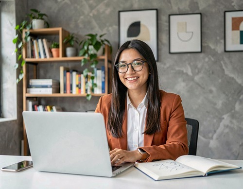 Woman in Orange Blazer at Laptop