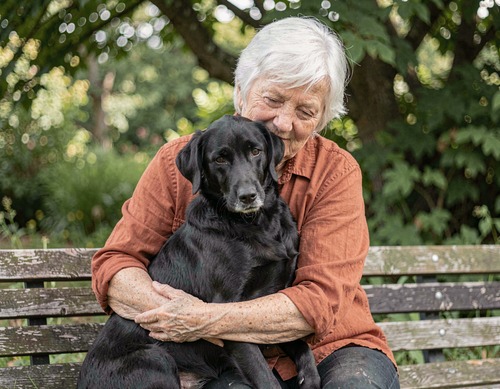 Senior Woman Hugging Black Dog