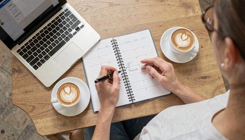 Person Planning Calendar with Laptop and Coffee