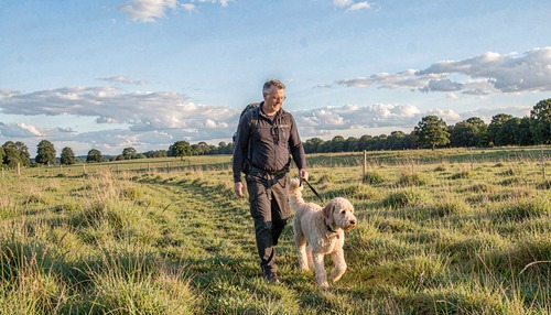 Man Walking Dog in Field
