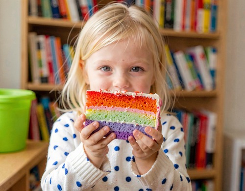 Child Holding Rainbow Cake Slice