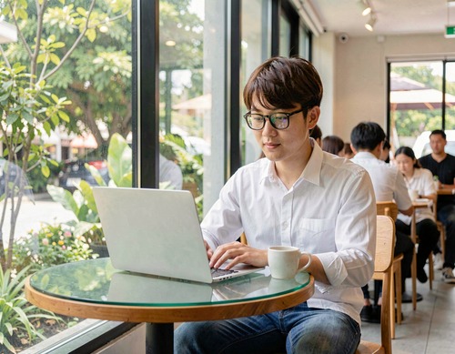 Young Man Working on Laptop in Café