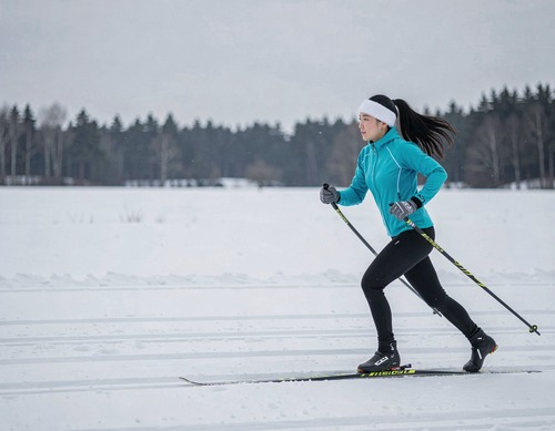 Asian Woman Cross-Country Skiing Through Snowy Field