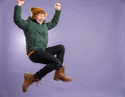 Jumping Man in Green Puffer on Lilac Background