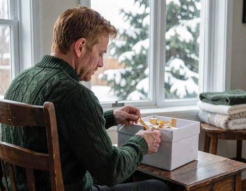 Man Unwrapping Gift by Snowy Window