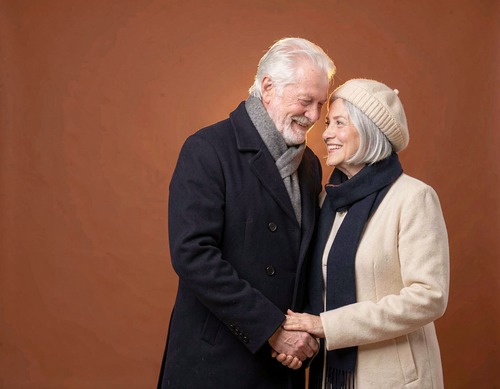 Senior Couple Holding Hands on Orange Background