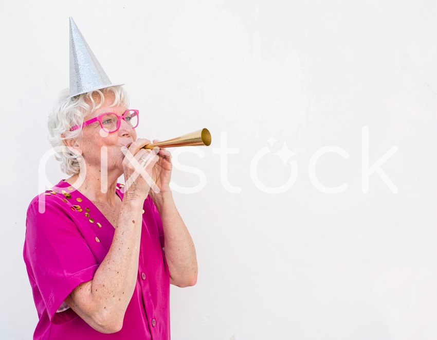 Senior Woman in Party Hat Blowing Gold Horn