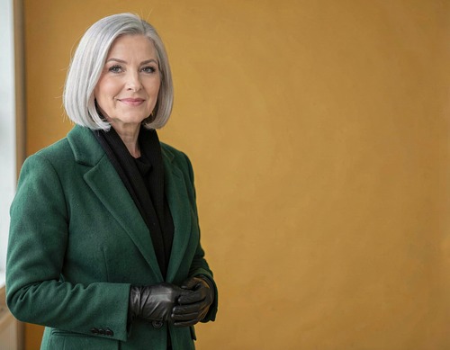 Silver-Haired Woman in Emerald Coat on Mustard Backdrop