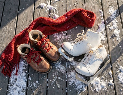 Snow Boots and Ice Skates on Wooden Porch
