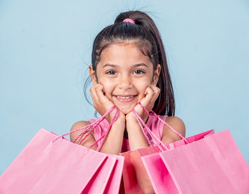 Happy Girl Holding Pink Shopping Bags Against Blue Background