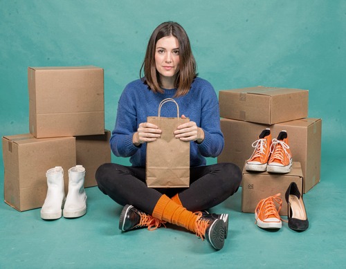 Smiling Woman with Shopping Bags in Teal Background