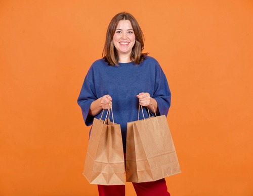 Woman Holding Shopping Bags Against Orange Background