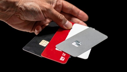 Hand Holding Four Colorful Credit Cards on Black Background