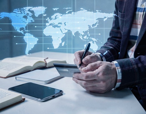 Businessperson Holding Credit Card and Writing with Digital Map Overlay