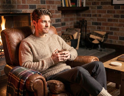 Young Man Relaxing With Hot Chocolate by Fireplace