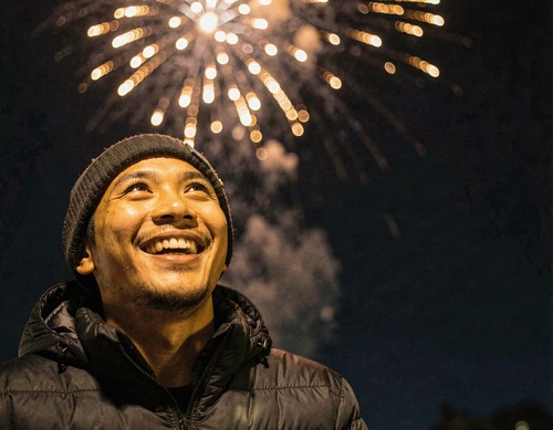 Young Man Smiling in Glow of Firework Burst